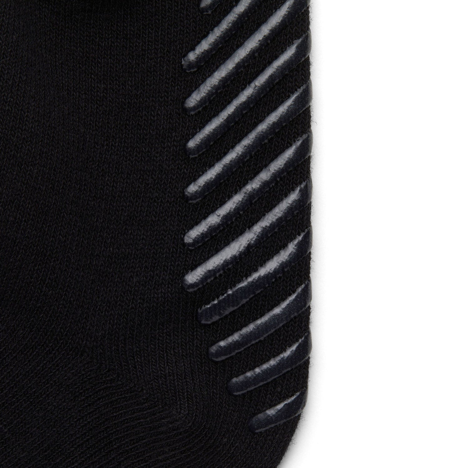 Close up of black anti slip kids socks with tread pattern on the bottom.