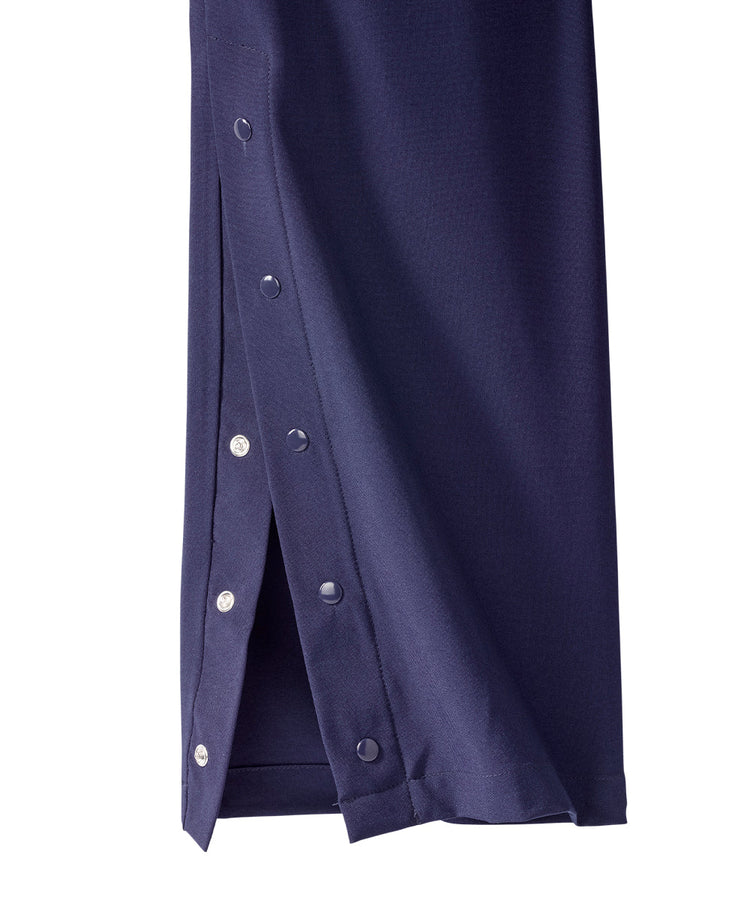 Close up of ankle of women’s navy blue pants with snaps along the side seam.