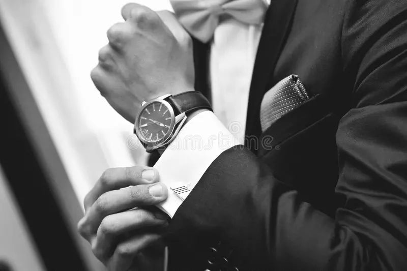 Black and white photo of a man putting on a watch