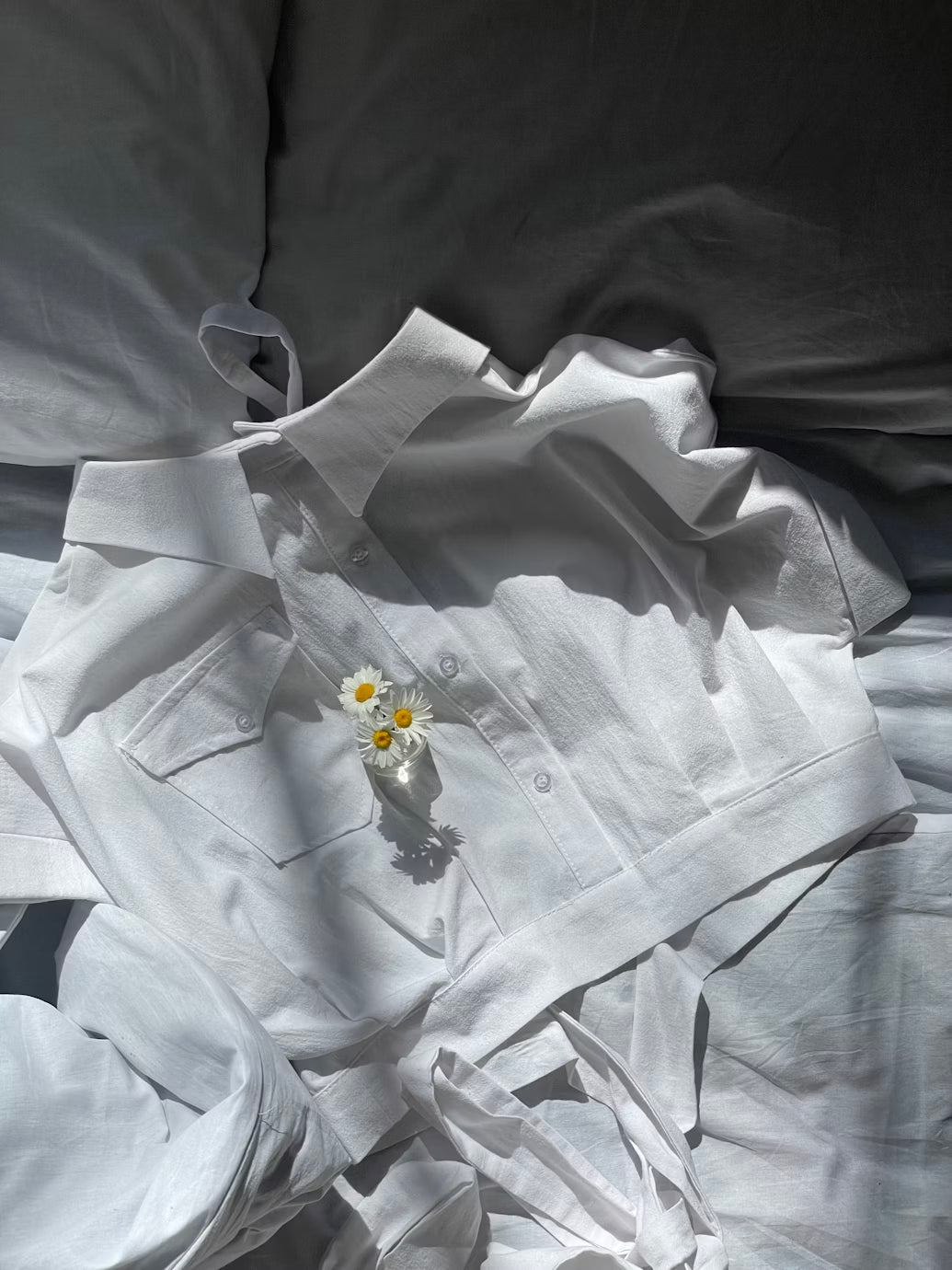 white top with white bedsheets and a flower placed on top