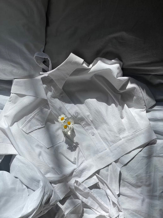 white top with white bedsheets and a flower placed on top