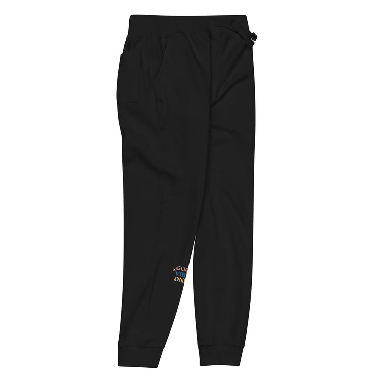 Side of full length Black sweat pant with pockets on side, featuring "Good vibes only" printed on right lower leg.