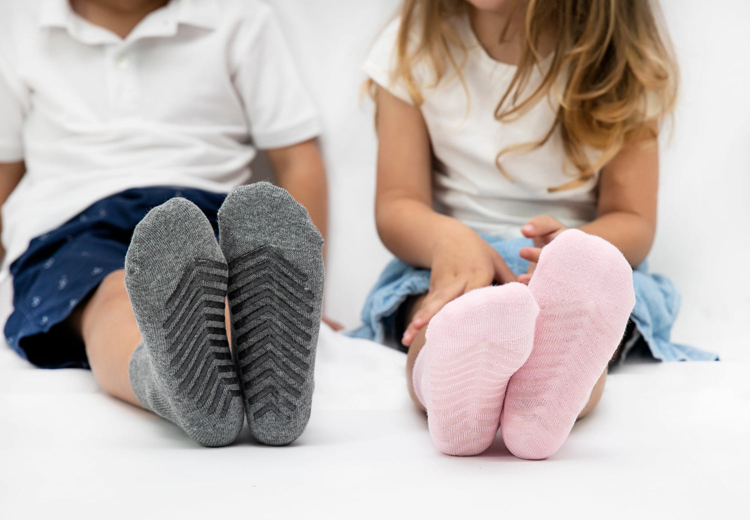 Children wearing anti slip socks with tread pattern on the bottom.