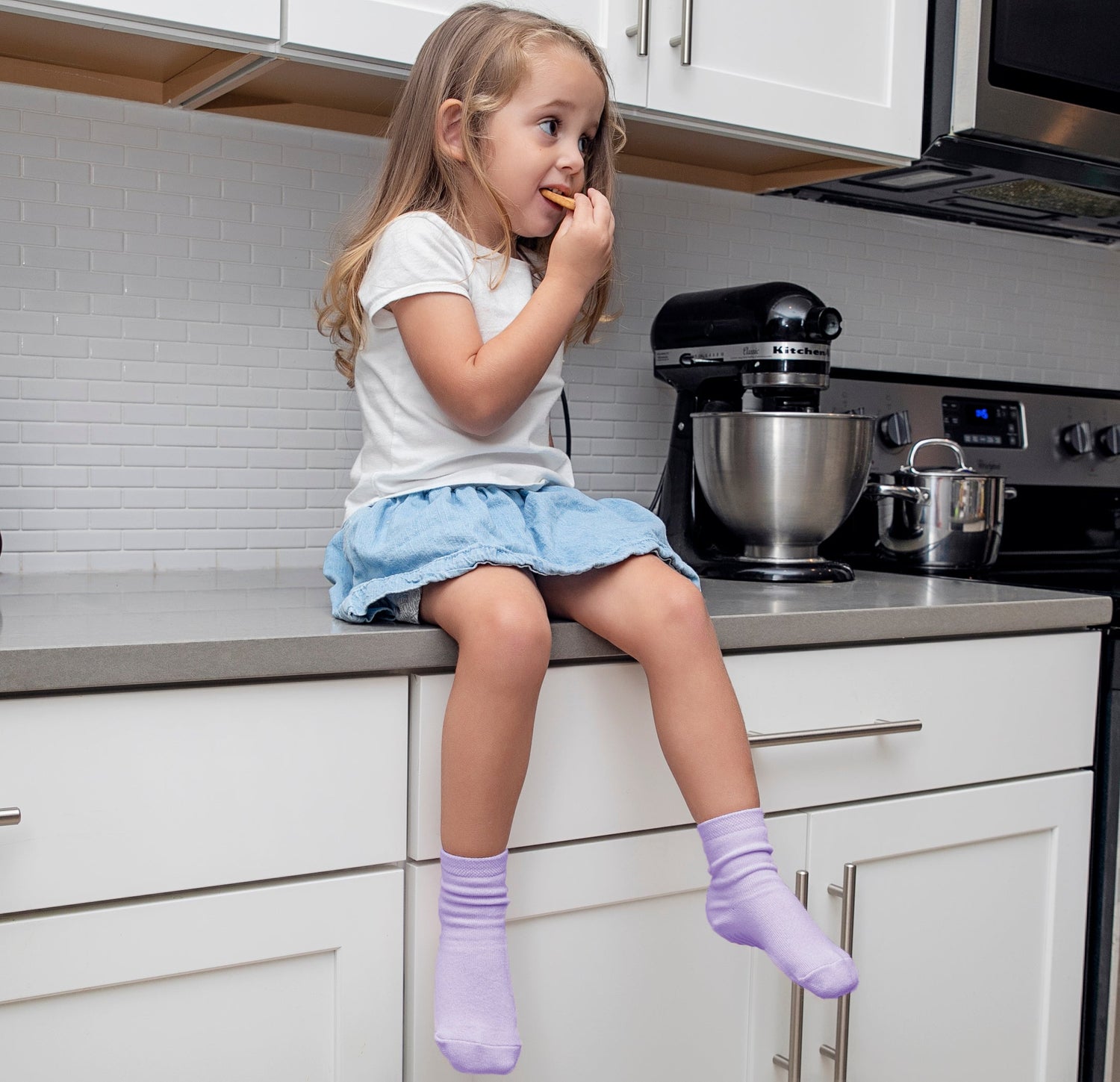 Child sitting on counter wearing light purple anti slip socks with tread pattern.