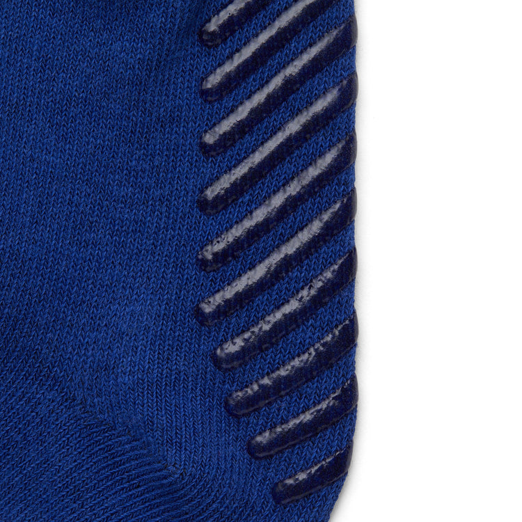 Close up of blue anti slip kids socks with tread pattern on the bottom.