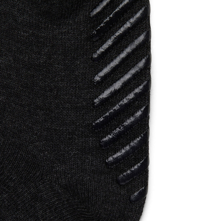 Close up of black anti slip kids socks with tread pattern on the bottom.