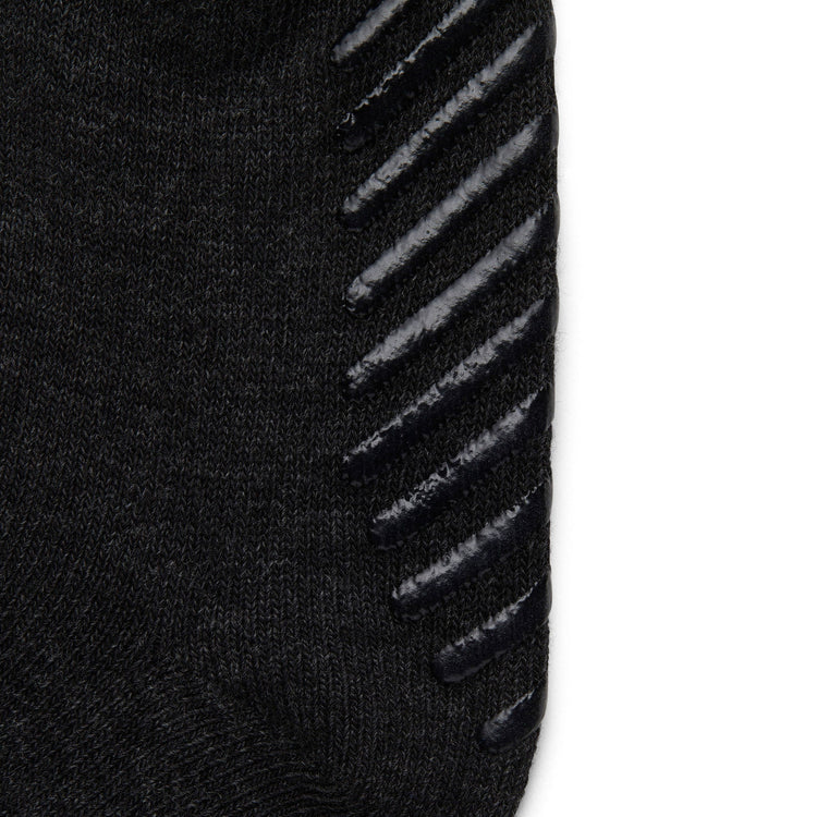 Close up of dark grey anti slip kids socks with tread pattern on the bottom.