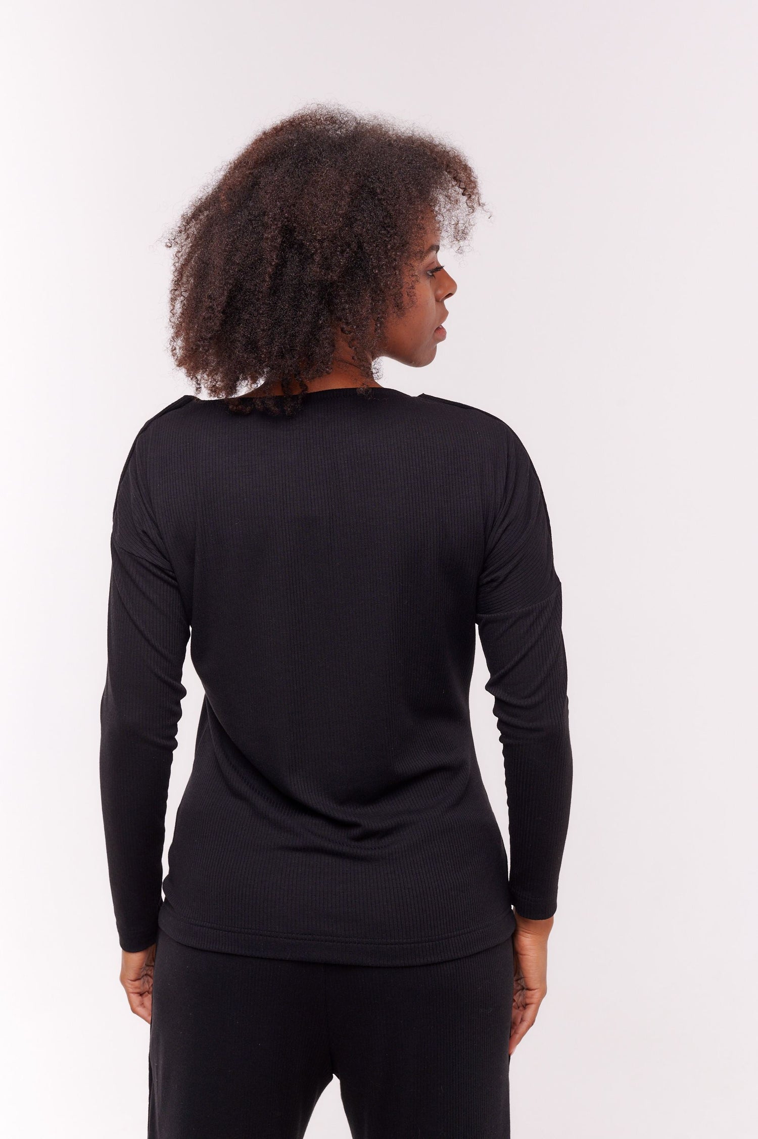 Woman facing backwards wearing black long sleeve top with shoulder snap closures.