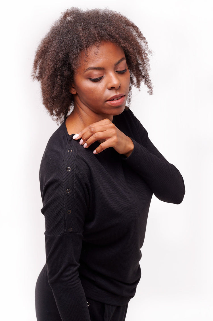 Close up of woman wearing black long sleeve top with shoulder snap closures.