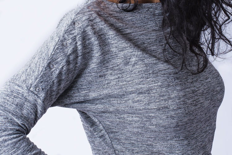 Close up of woman wearing grey long sleeve top with shoulder snap closures.