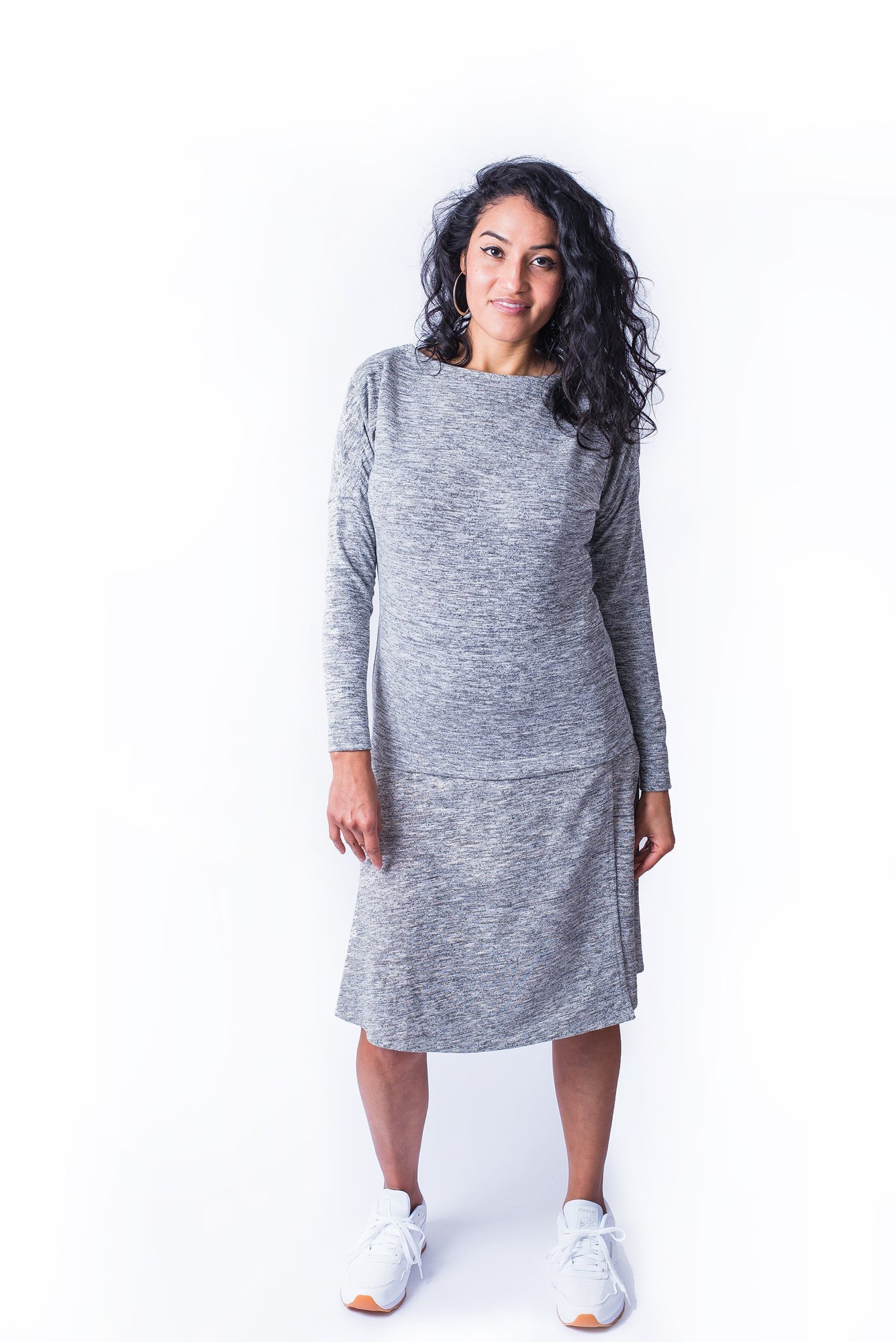 Woman wearing grey long sleeve top with shoulder snap closures and matching grey skirt.