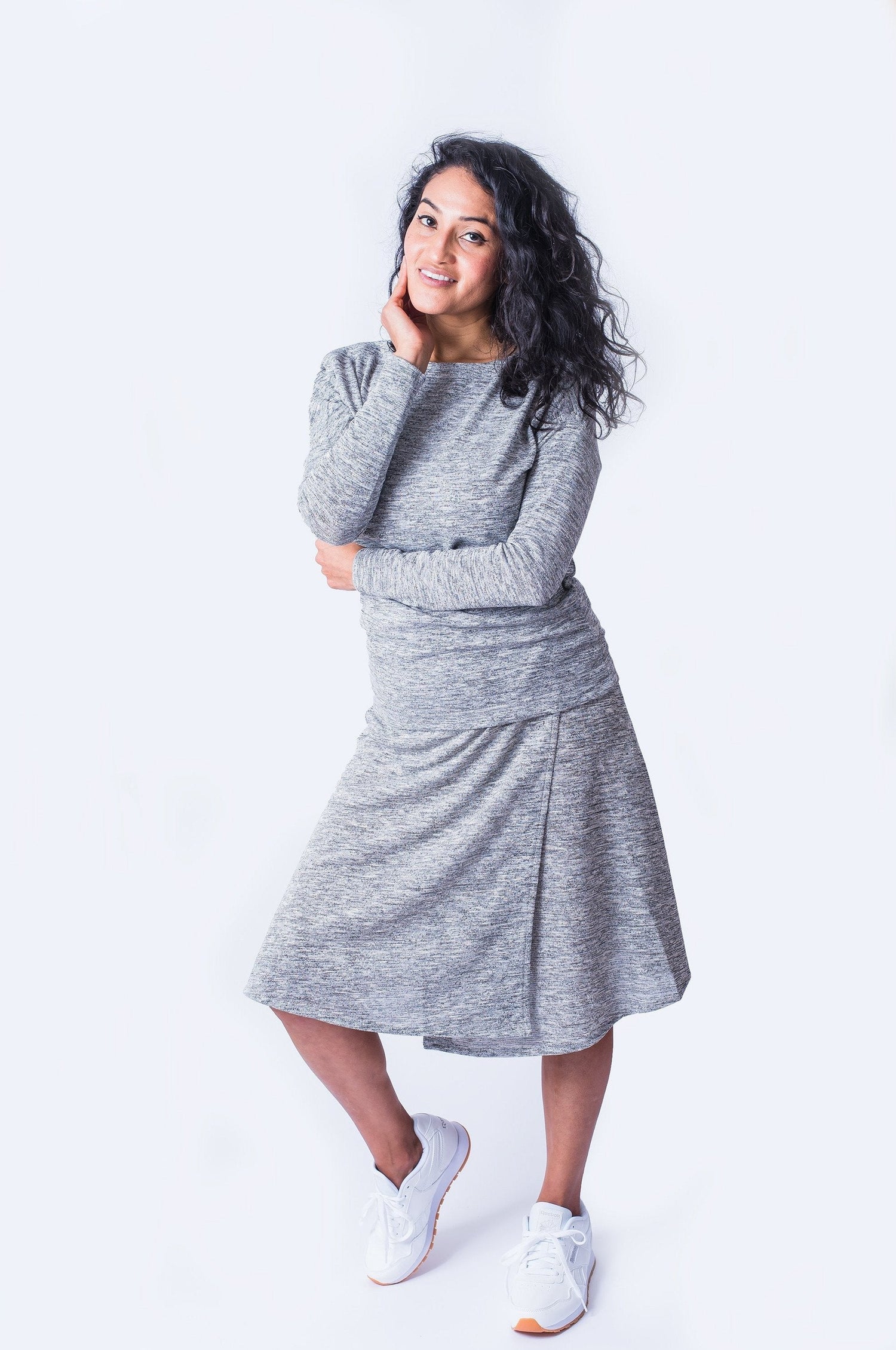 Woman posing wearing grey long sleeve top with shoulder snap closures and matching grey skirt.