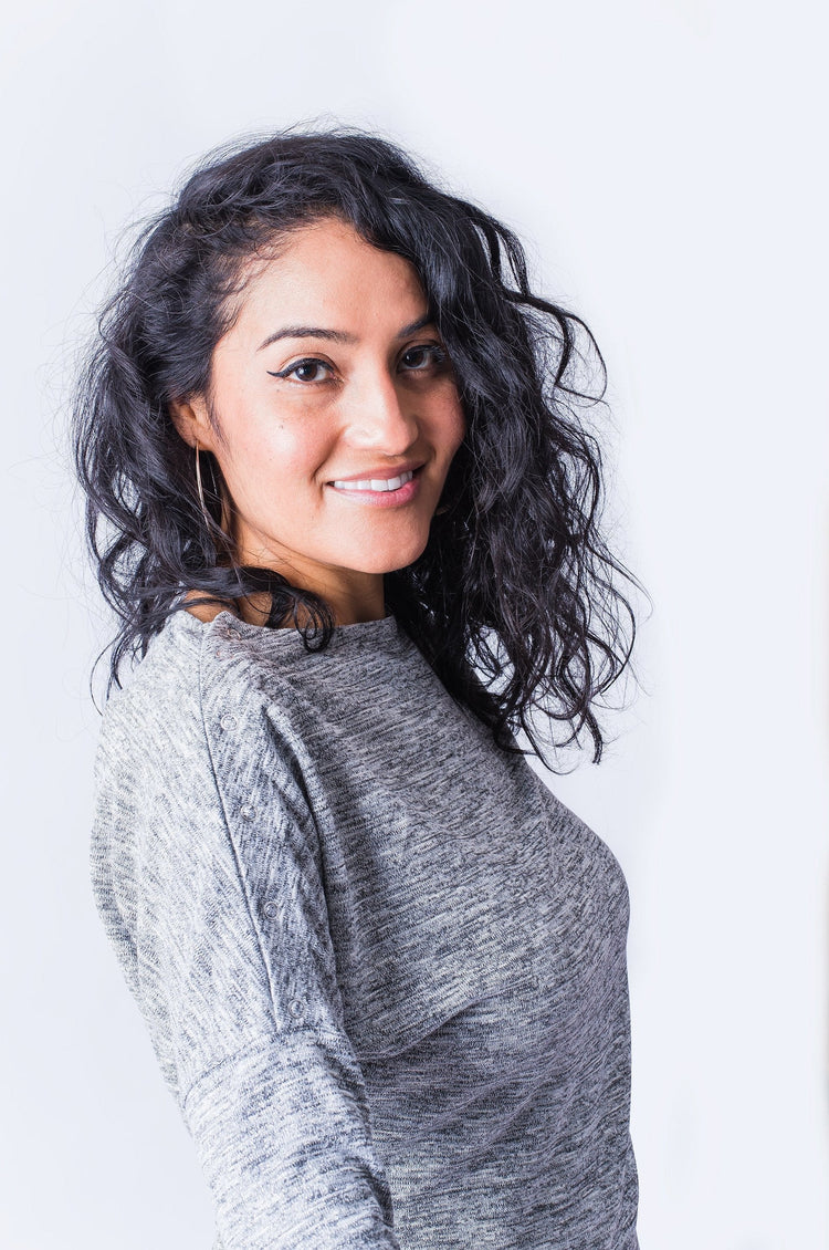 Close up of woman wearing grey long sleeve top with shoulder snap closures.