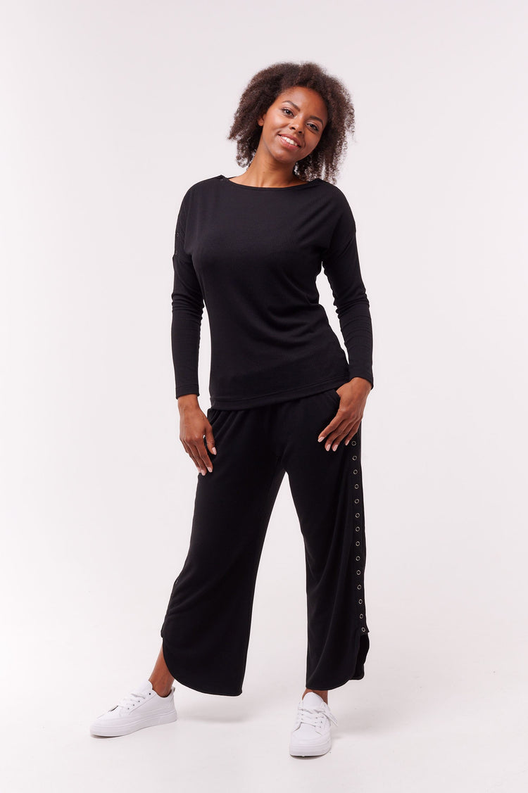 Woman posing wearing black long sleeve top with shoulder snap closures and matching bottoms.