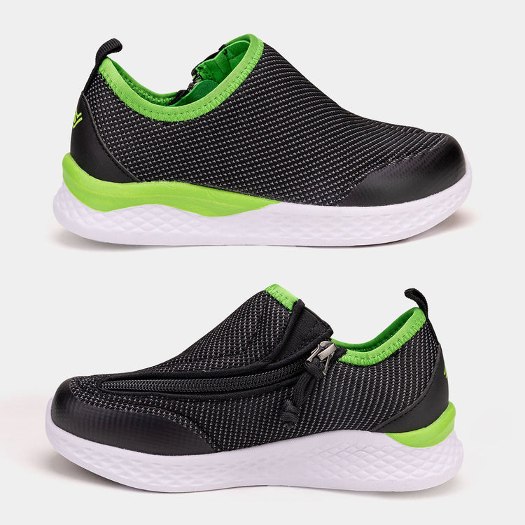 Black kids shoe with white bottom, green accents, and side zipper access.