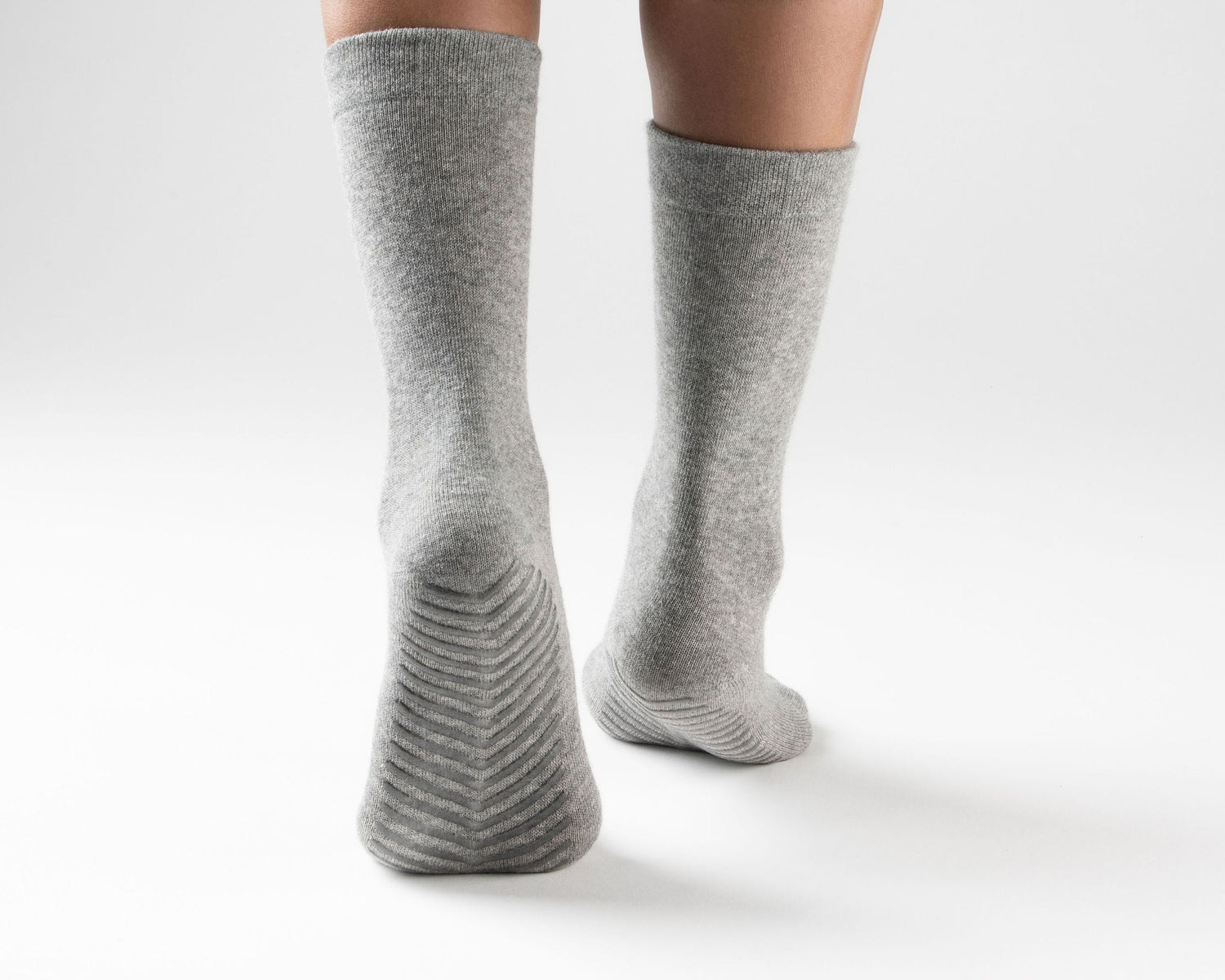 Model wearing light grey anti slip socks with tread pattern on the bottom.