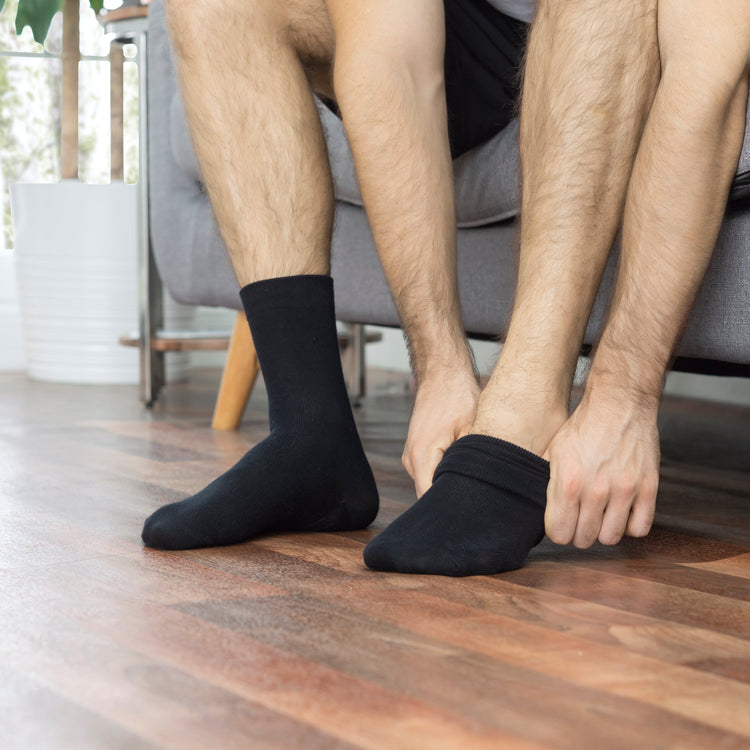 Model putting on black anti slip socks with tread pattern on the bottom.