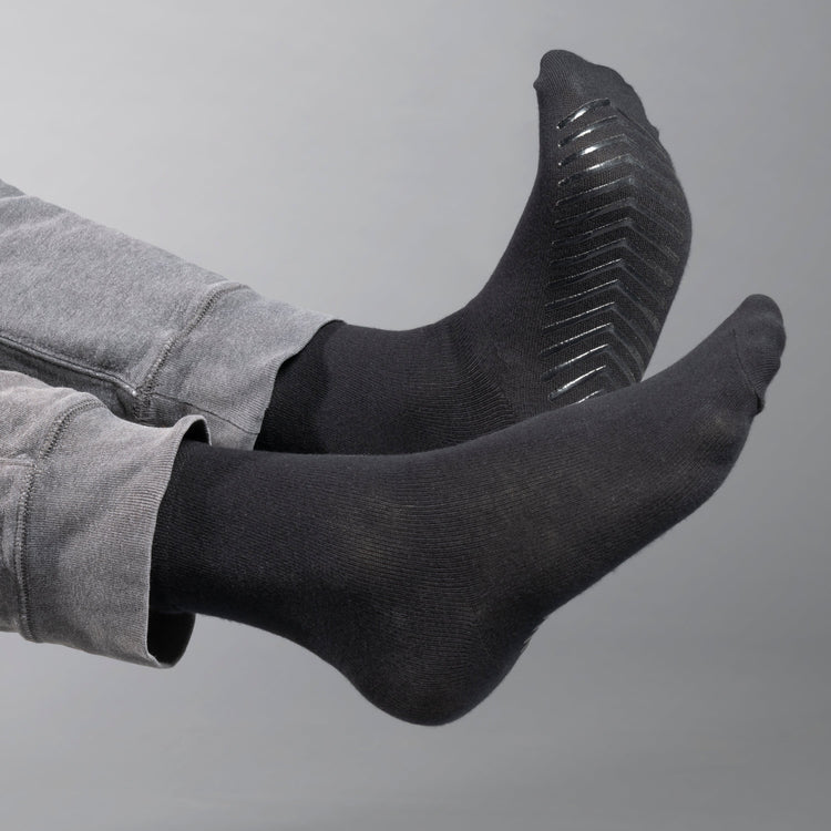 Model wearing black anti slip socks with tread pattern on the bottom.
