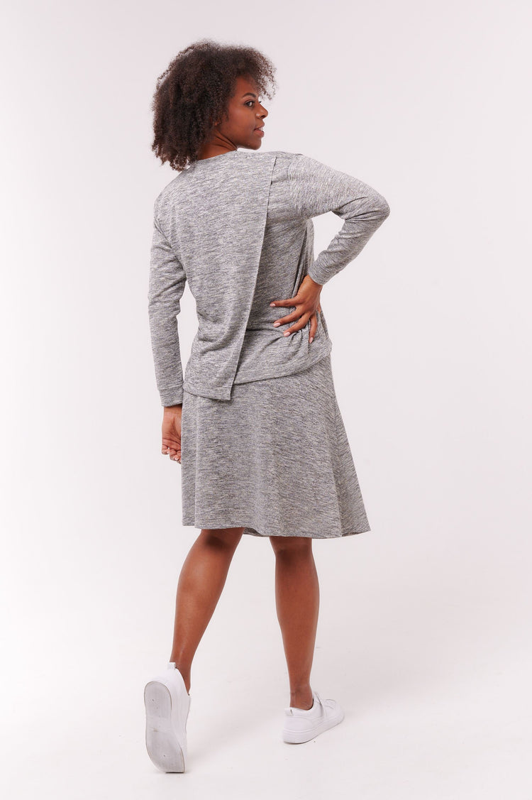 Woman facing backwards wearing grey wrap skirt with snap closure waist band and matching top.