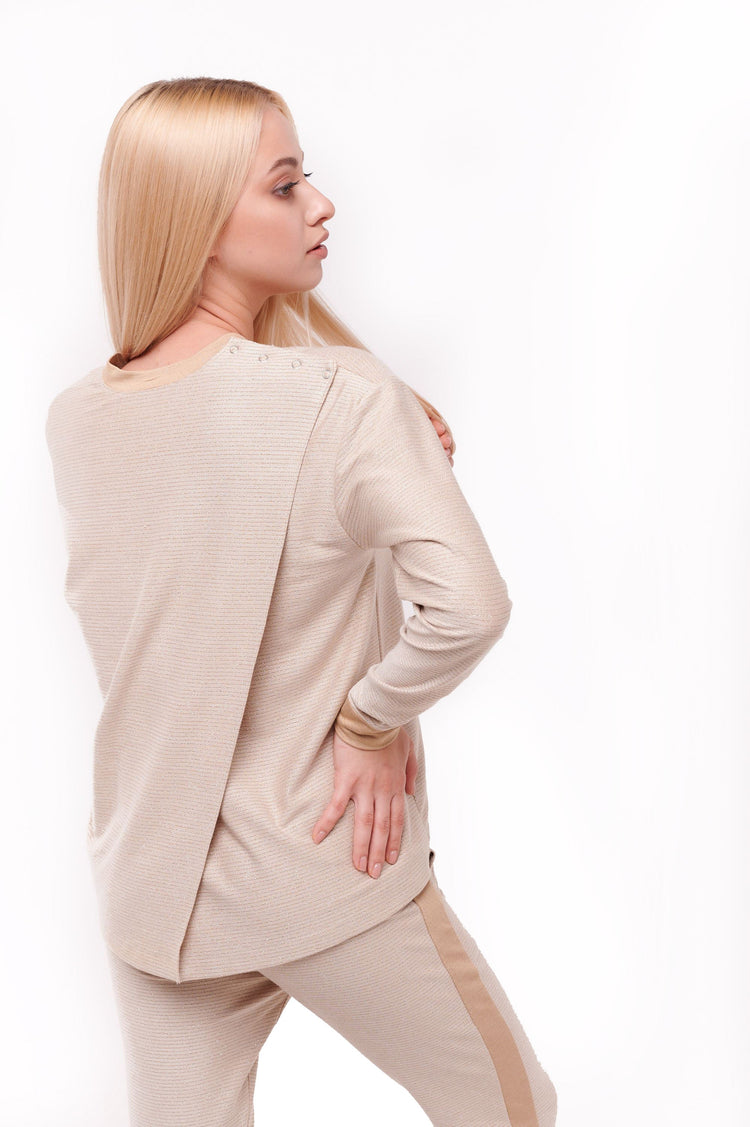Woman posing wearing cream long sleeve top with back overlap and shoulder snap closures.