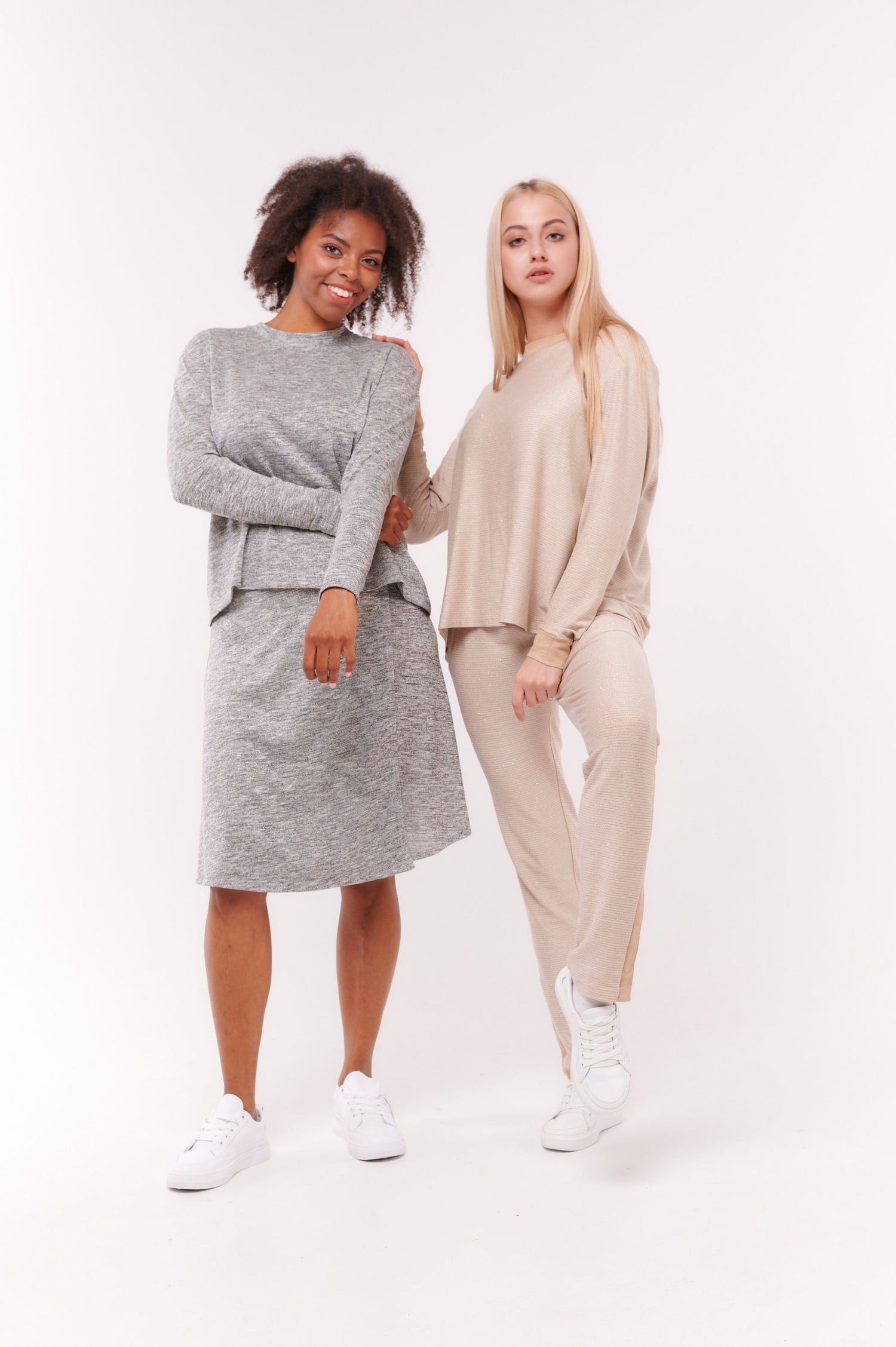 Two woman posing wearing grey and cream leisure clothing.