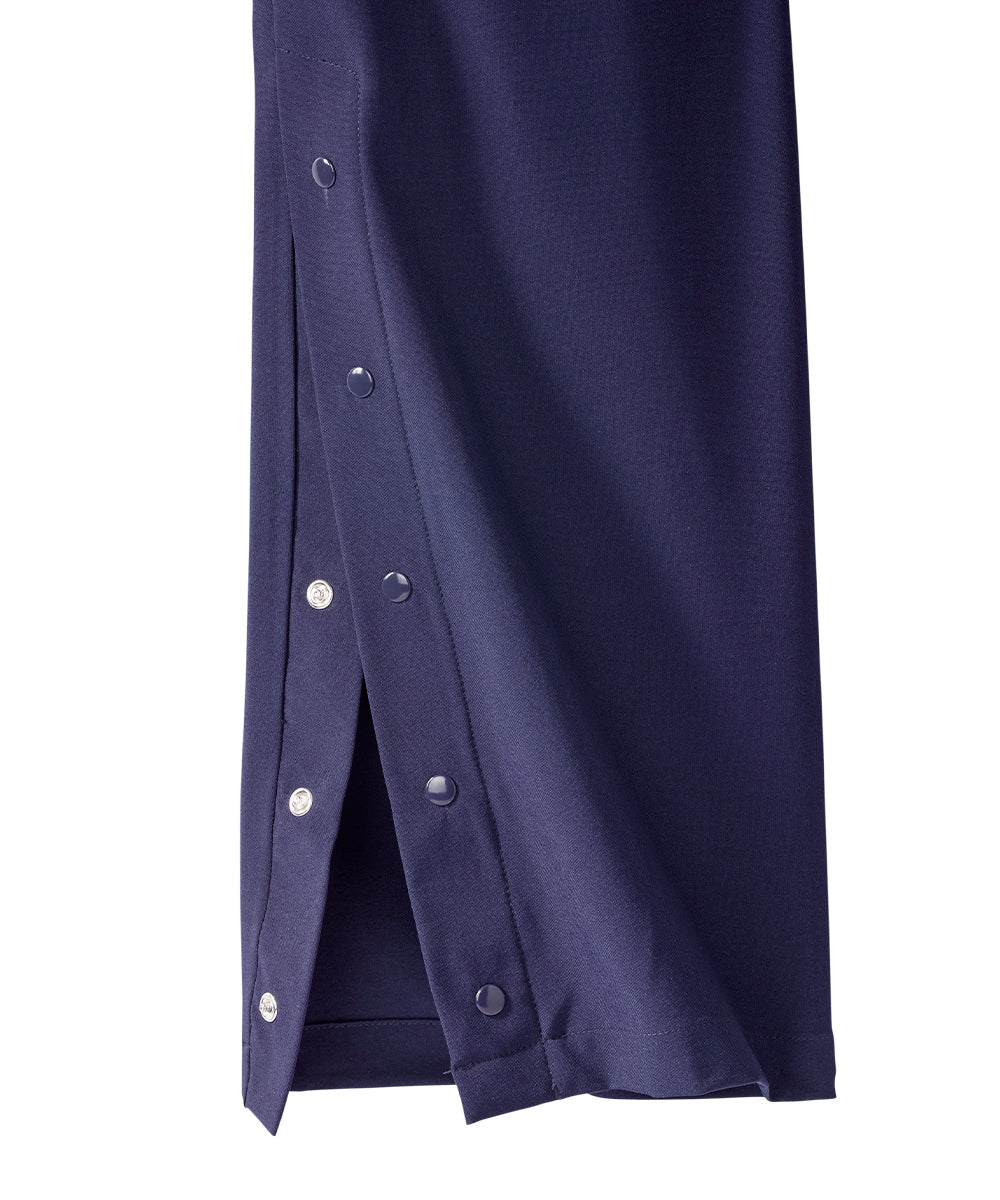 Close up of ankle of women’s navy blue pants with snaps along the side seam.