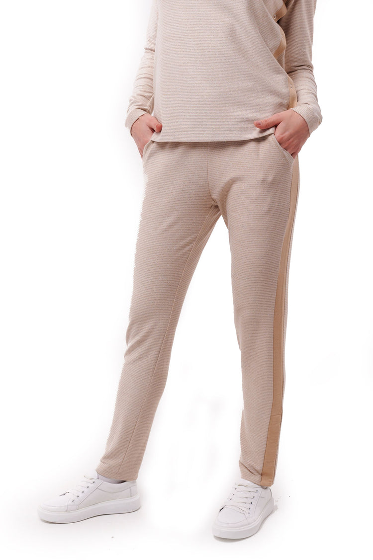Woman wearing cream full length slim pants with ankle snap closures.