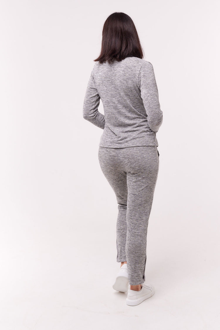 Woman facing away wearing grey full length pants with ankle snap closures and matching top.