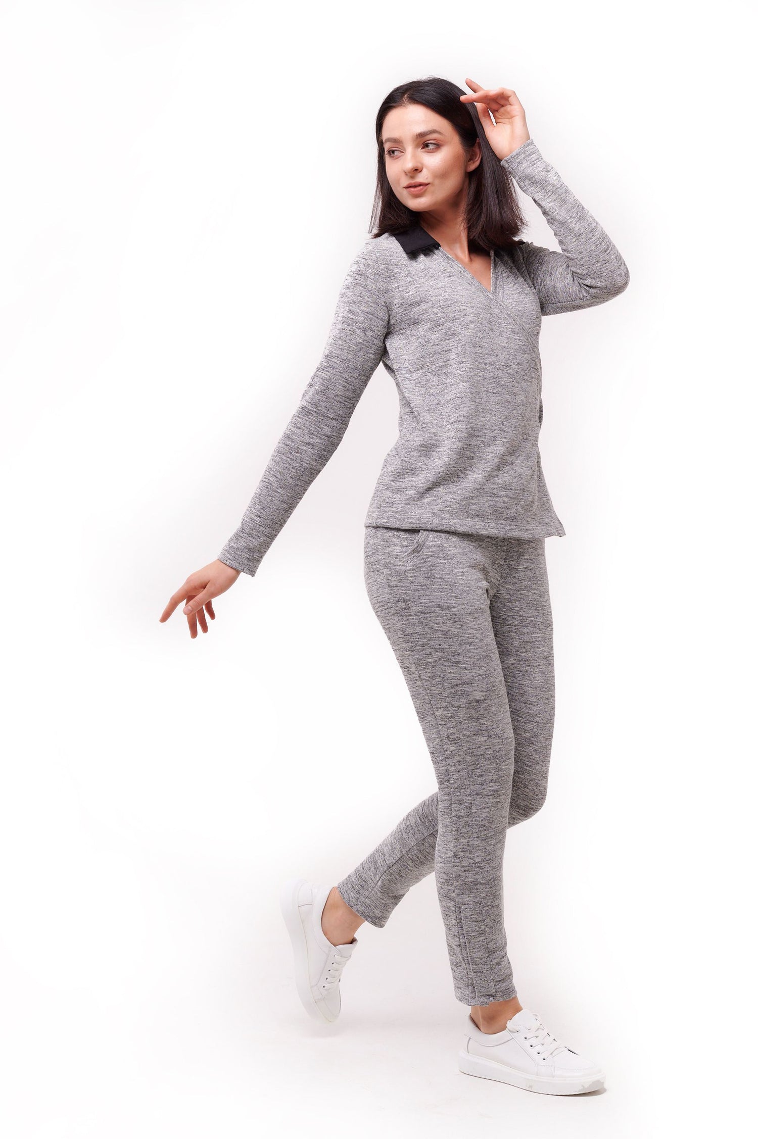 Woman posing wearing grey full length slim pants with ankle snap closures and matching top.