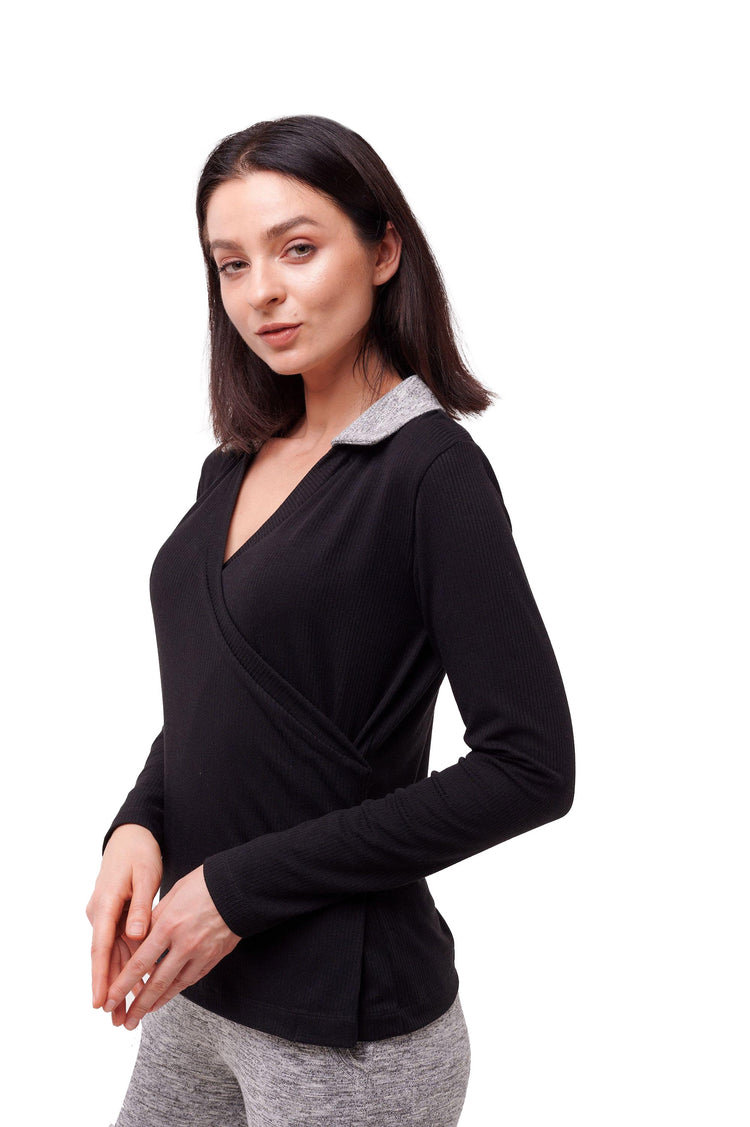 Woman wearing black long sleeve wrap top with grey collar and side snap closures.