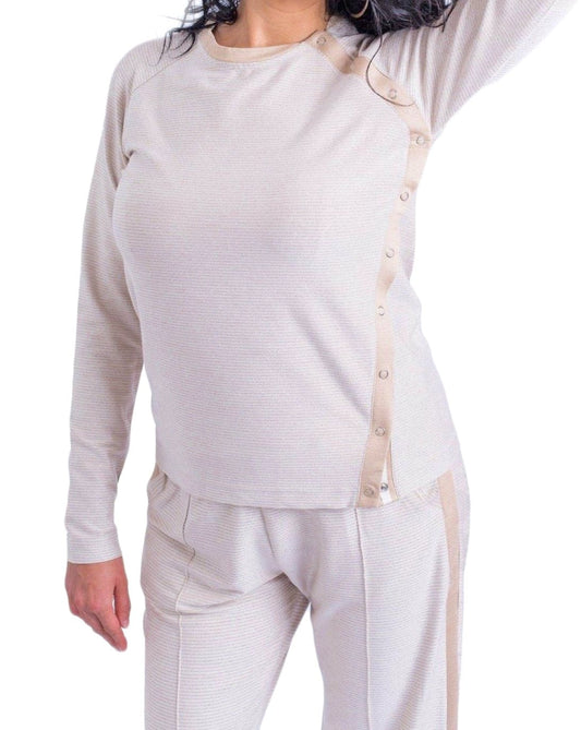 Woman wearing cream long sleeve crewneck top with side snap closures.
